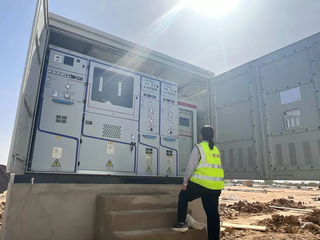 Engineer in a high-visibility vest inspecting an electrical switchgear unit on site